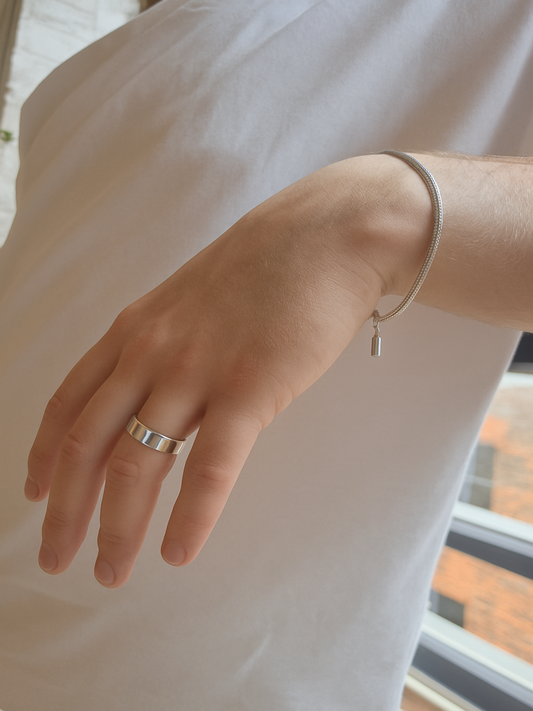 Hand wearing a silver ring with a blurred background